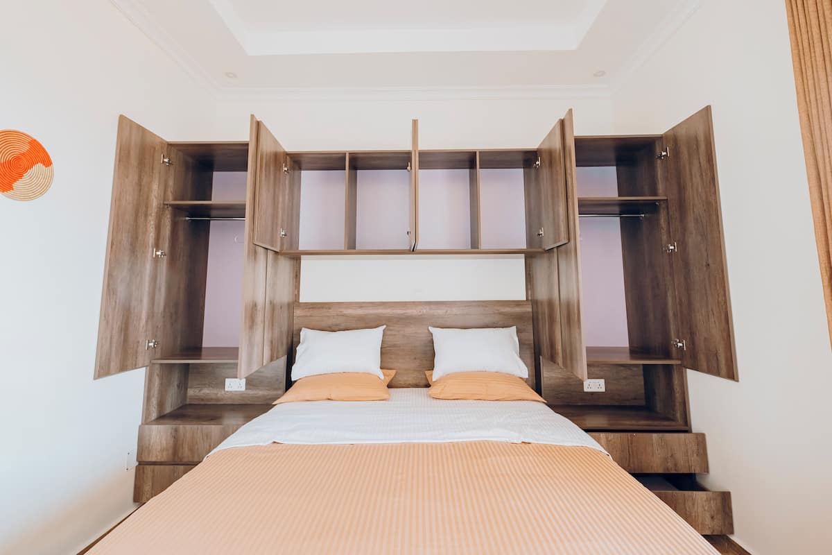 A bedroom with a bed, wooden headboard, and built-in storage cabinets.