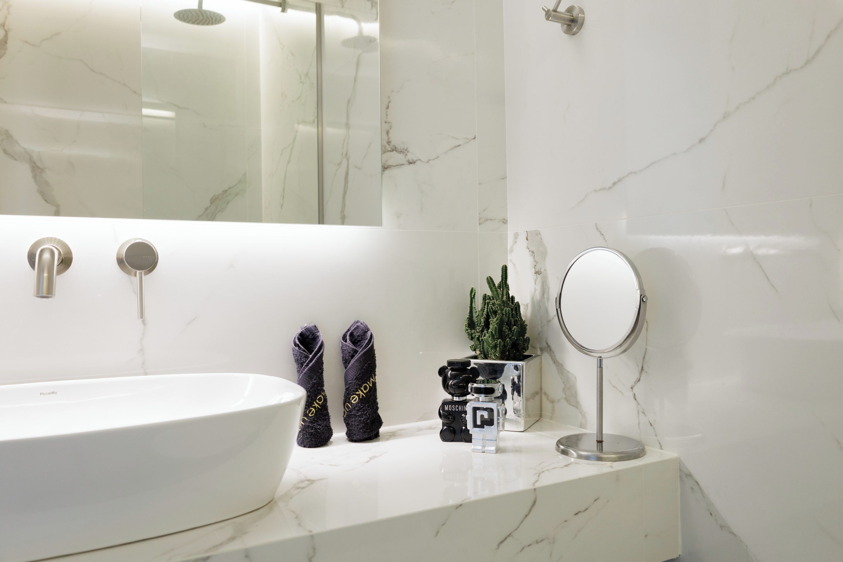 A modern bathroom with a large white bathtub, a mirror, and a small potted plant.