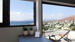 A balcony with a view of the sea and town, a small table with a cup, and two potted plants. - Athens Riviera Suites (Saronikos)