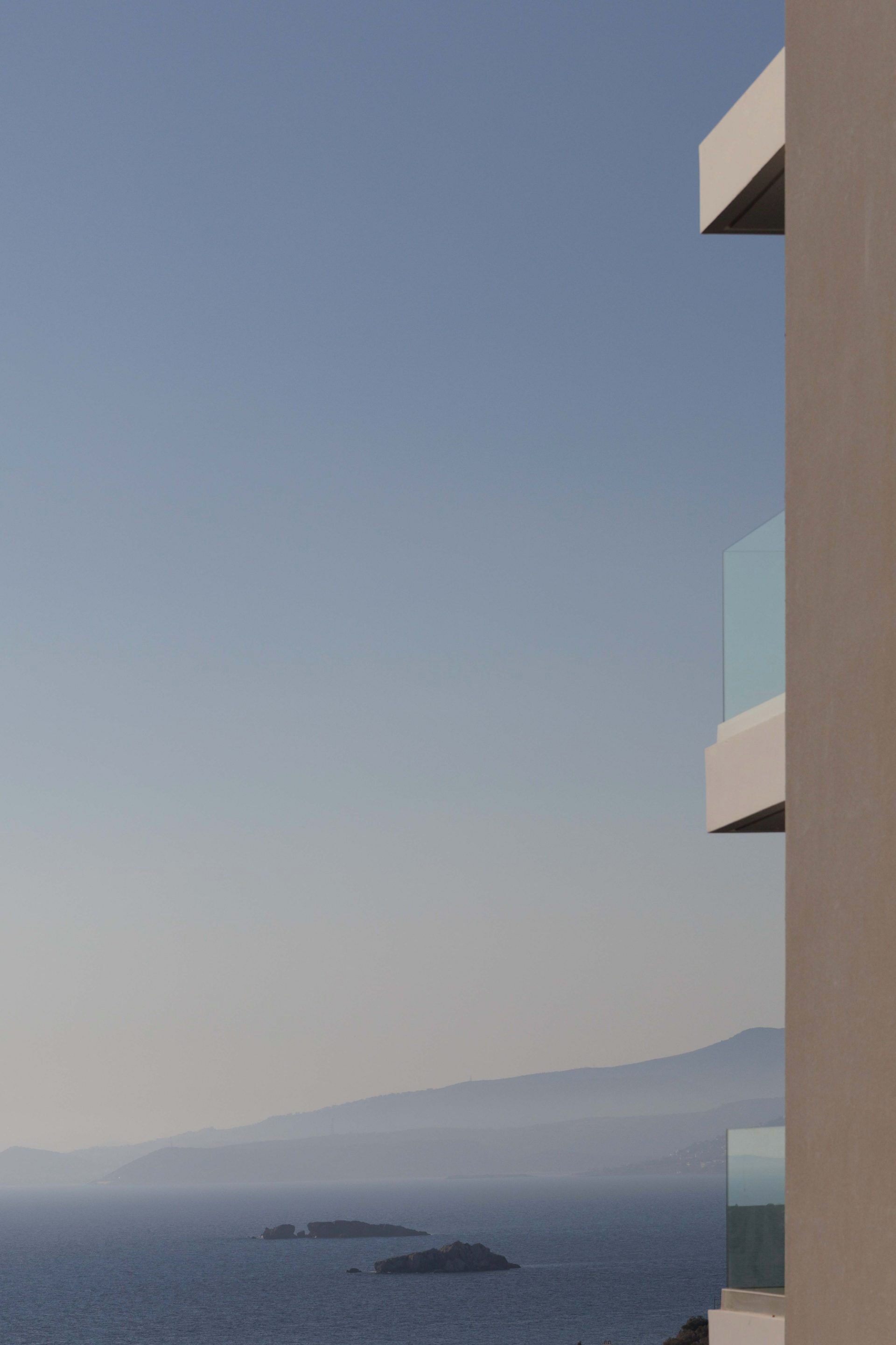 A modern building with a clear view of the sea and distant mountains.