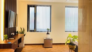 Un salon moderne avec un téléviseur à écran plat, des meubles en bois, un petit radiateur et des plantes en pot.