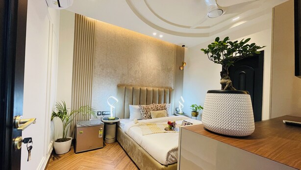 Une chambre moderne avec un lit, des tables de chevet, une plante en pot et un ventilateur de plafond.