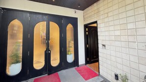 Une entrée moderne avec une porte noire dotée d’un panneau en verre, un tapis rouge et un mur recouvert de carreaux.