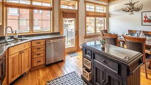 A spacious kitchen with wooden cabinets, a dishwasher, and a dining area with a table and chairs. - Cross-Country Ski Out the Back Door (Big Sky)