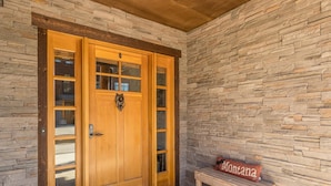 A wooden front door with glass panels and a stone wall. - Cross-Country Ski Out the Back Door (Big Sky)