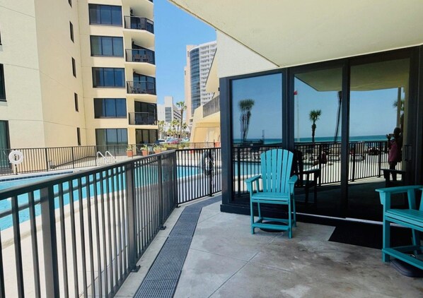 A balcony with a pool, outdoor seating, and a view of the ocean.