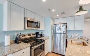 A modern kitchen with stainless steel appliances, granite countertops, and white cabinetry.