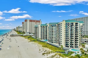 Ein Strandhotel mit mehreren Hochhäusern, einem Sandstrand und blauem Himmel.