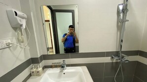 A bathroom with a white sink, a handheld dryer, and a shower.
