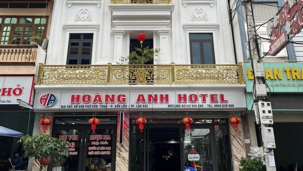 A hotel with a white facade, multiple balconies with red lanterns, and a sign for 'Hoàng Anh Hotel'.