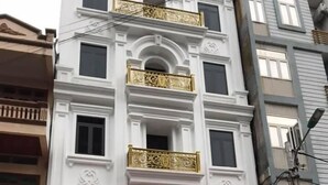 A hotel with a white facade, gold decorative elements, and a sign reading "HOANG ANH HOTEL".