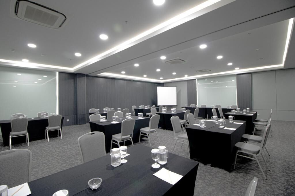 A conference room with multiple tables and chairs, equipped with projectors and presentation screens.