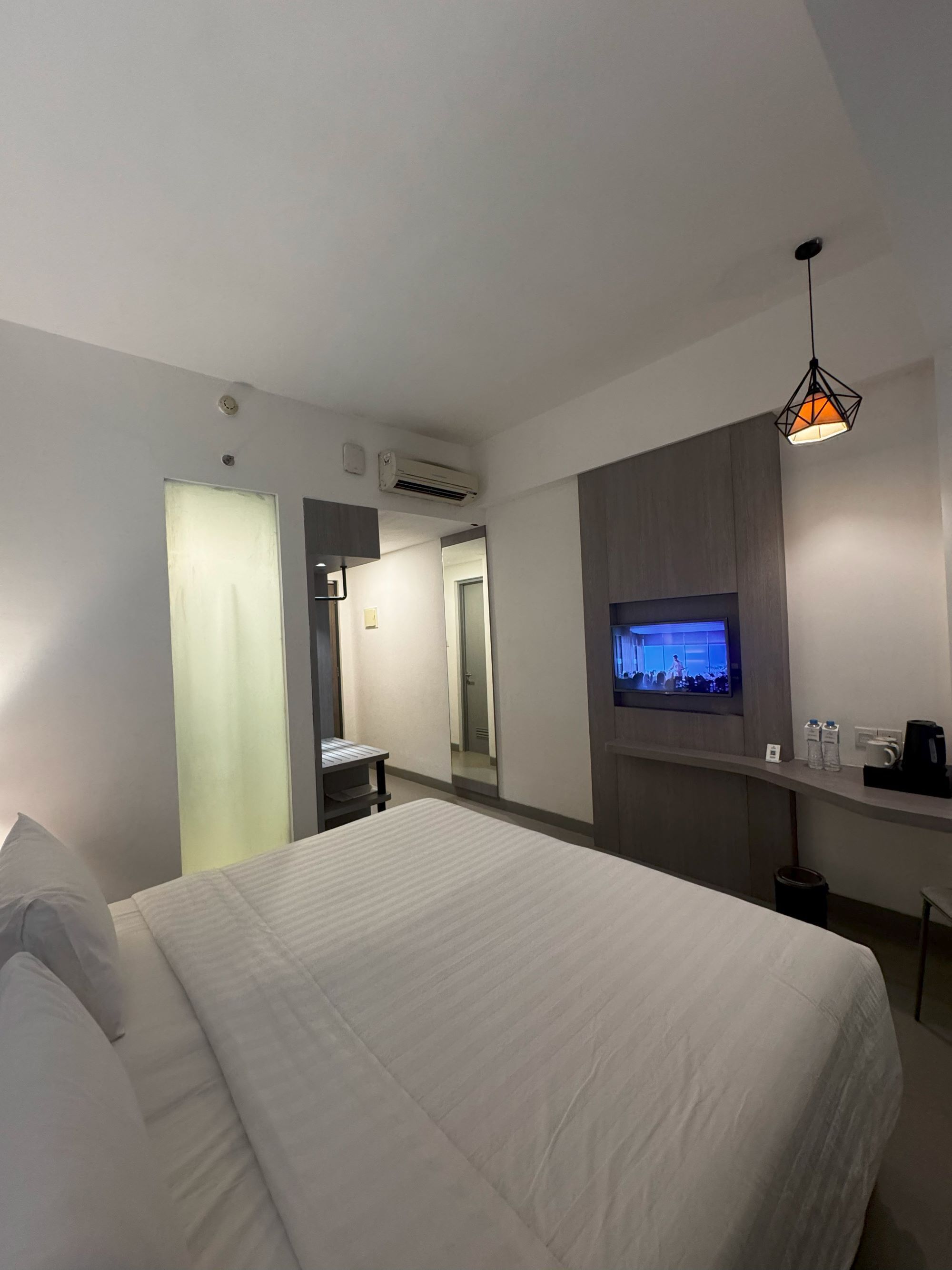 Une chambre d’hôtel avec un lit, un bureau avec une télévision et un miroir.