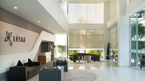 A spacious lobby with a reception desk, seating area, and large windows offering views of the outdoors. - Laska Hotel Subang (Subang)