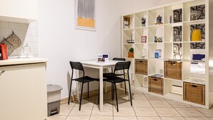 A modern kitchen with a dining area, featuring a white table, black chairs, and a white cabinet with a red item on top. - Via Nilo 30 in Naples (Naples)