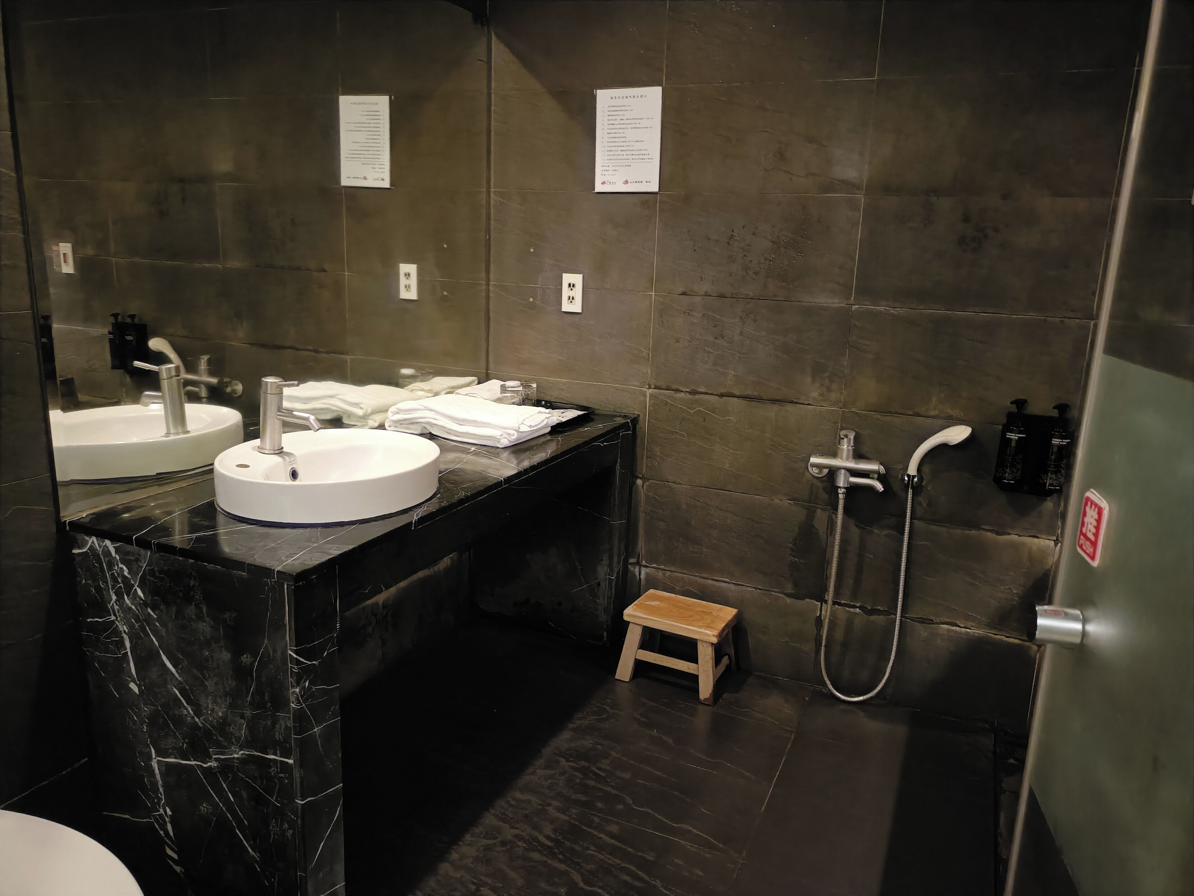 Un baño moderno con dos lavamanos, una ducha y un taburete de madera.