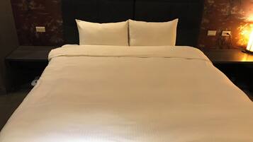 A neatly made bed with white linens in a hotel room.