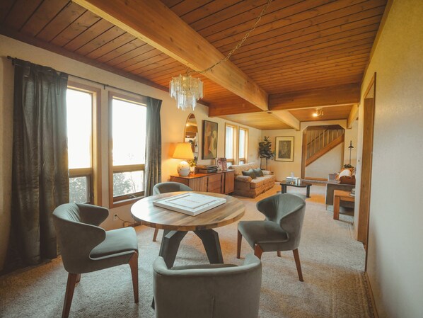 A cozy living room with a wooden ceiling, a round wooden table, and comfortable seating.