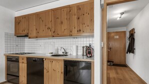 Une cuisine de taille réduite, dotée de meubles en bois, d’un lave-vaisselle, d’une cuisinière et d’un évier.