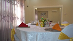 Zona pranzo con tavoli rotondi apparecchiati per un pasto, con tovaglie bianche e nastri gialli.
