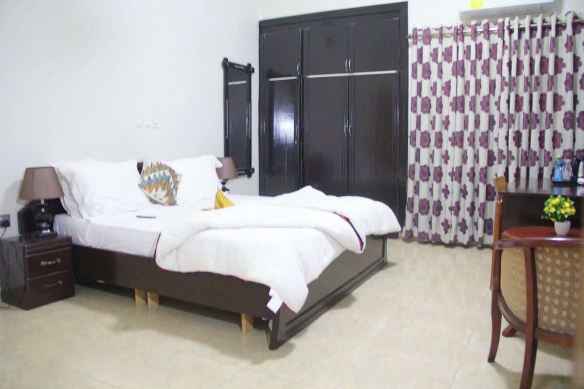 Une chambre à coucher comprenant un lit, des tables de chevet, une armoire et une chaise.