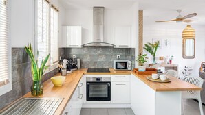 Una cocina moderna con armarios blancos, horno empotrado, microondas y encimera de madera.