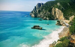A coastal landscape with clear turquoise waters, rocky cliffs, and a sandy beach. - Lovely 2 bed apartment in quiet Lisbon South Bay - Close to the best beaches! (Baixa da Banheira)