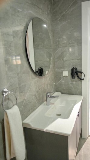 Un baño con lavamanos blanco, un espejo y un toallero.