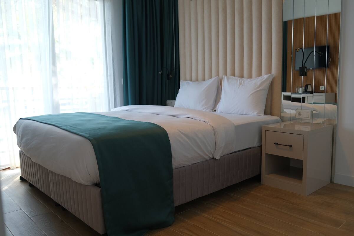 Habitación de hotel con cama, mesita de noche y espejo.