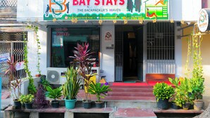 A hotel named "Bay Stays" with a signboard, a calendar, and potted plants in front. - Roscotel Bay Stays 2BHK Near White Town (Puducherry)