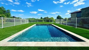 A rectangular swimming pool with a stone border, surrounded by a white fence and green grass. - Huge estate with swimming pool, cinema, reception hall, boules pitch and more (Nérac)