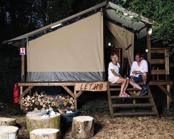 Une cabane rustique dotée d’une grande auvent en toile sur laquelle est inscrit le mot « LETHO ».