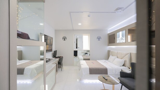 A modern hotel room with a bed, a desk, a chair, a small table, and a mirror.