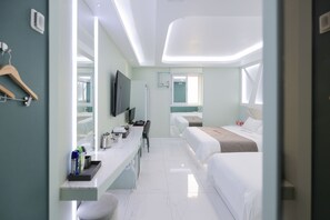 Una habitación de hotel moderna con un espejo grande, un televisor de pantalla plana, un escritorio con artículos de aseo, dos camas y una ventana.