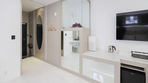 A modern hotel lobby with a large mirror, a flat-screen TV, and a reception desk.