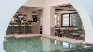 An indoor swimming pool with a bar area and seating. - Elounda Stories Boutique Hotel (Agios Nikolaos)