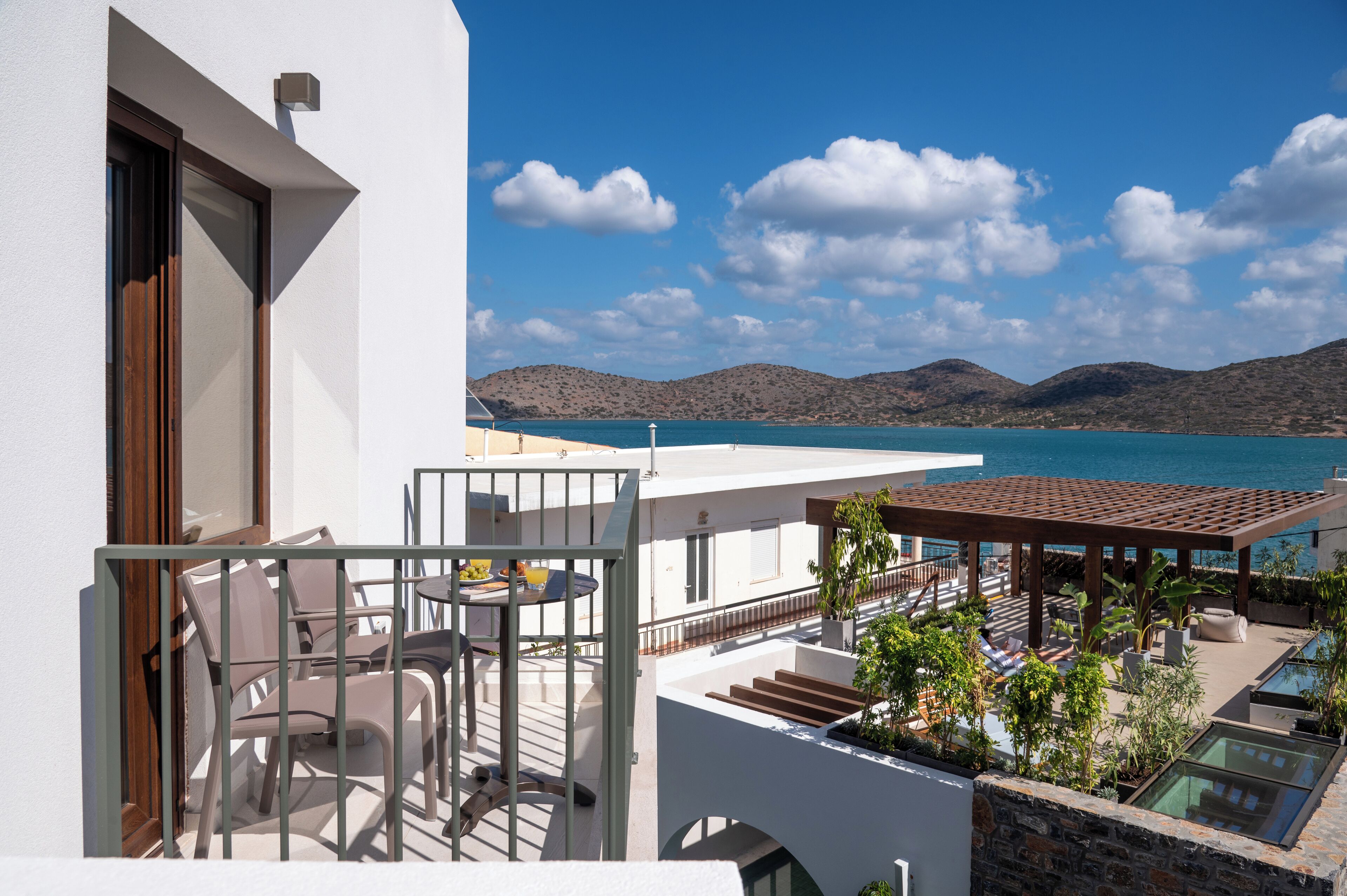 Un balcone con posti a sedere all'aperto, una piscina e vista sul mare e sulle colline.