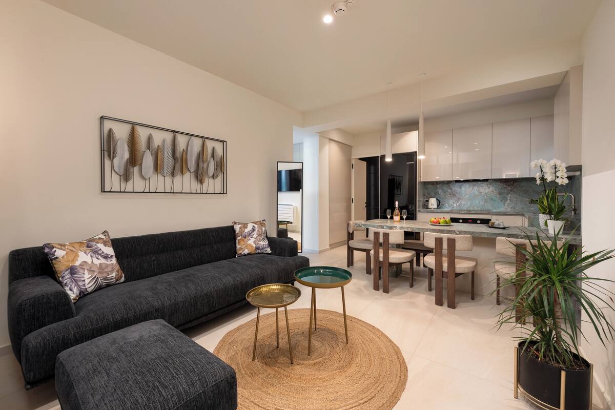 Ein modernes Wohnzimmer mit einem dunkelgrauen Sofa, einem Couchtisch und einem Essbereich mit Marmorplatte.