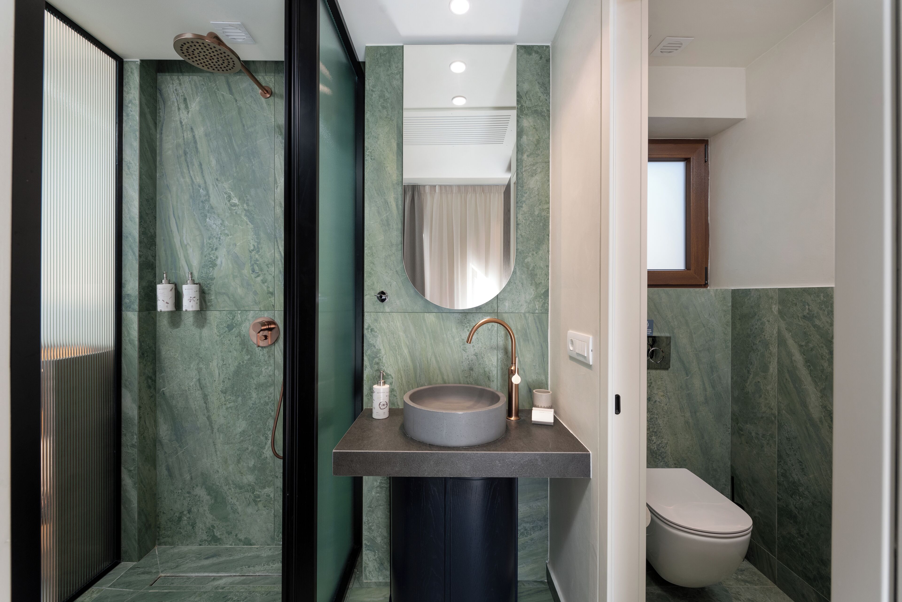 Un baño moderno con un lavabo redondo, un inodoro y una zona de ducha.