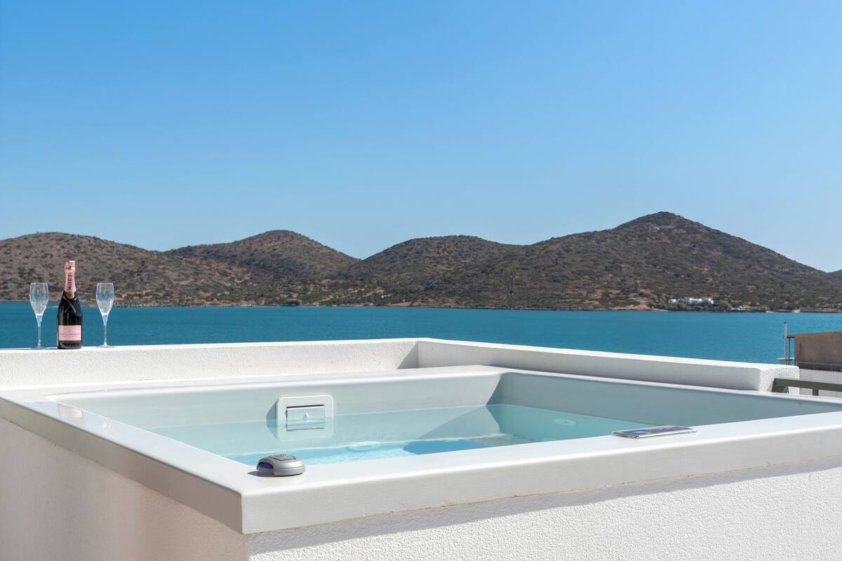 Ein moderner Whirlpool im Freien mit freiem Blick auf das Meer und die dahinterliegenden Berge.