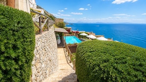 A stone staircase leading to a pool area with a view of the sea. - Villa Mare Blu With Sea View (Praiano)
