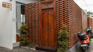A brick wall with a wooden door, a sign with a name, and a parked motorcycle. - Padi Villa Ubud, a Modern Pool Retreat (Ubud)
