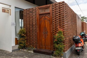 A brick wall with a wooden door, a sign with a name, and a parked motorcycle.