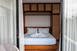 A hotel room with a bed, a wooden headboard, and a view through a glass door.