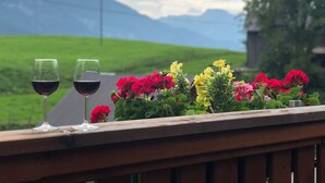 Une terrasse en bois avec deux verres à vin et une variété de fleurs aux couleurs vives.