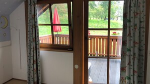 Une pièce avec une porte en bois donnant sur un balcon doté d’une balustrade en bois.