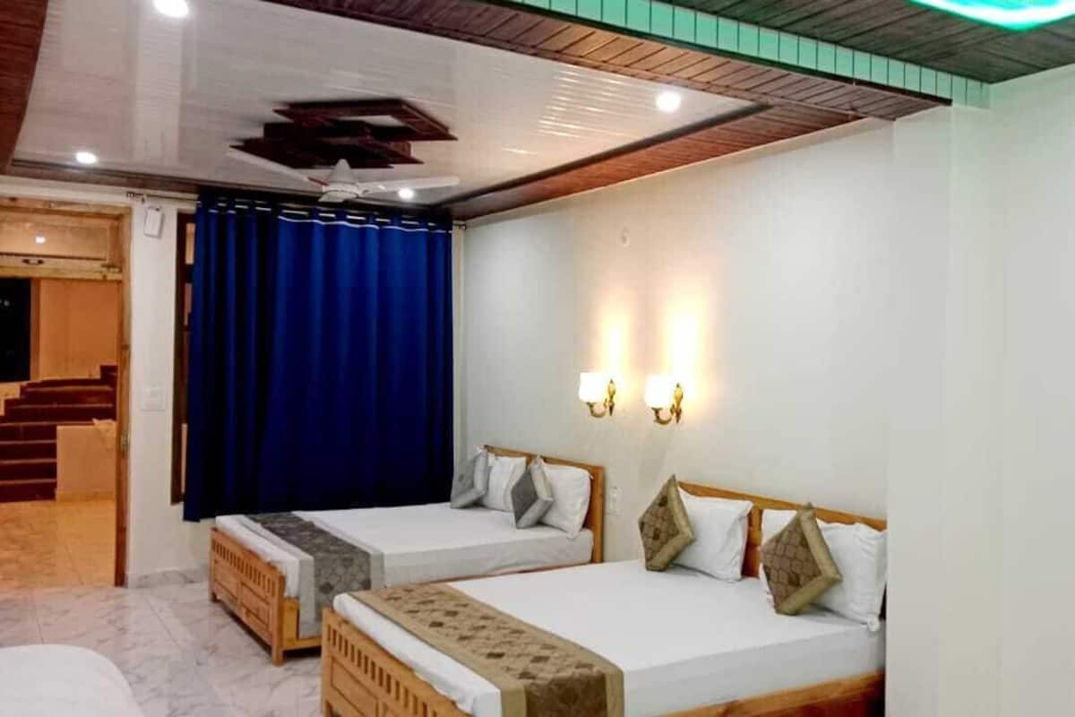 A hotel room with two single beds, a wooden headboard, a ceiling fan, and a staircase leading to an outdoor area.
