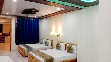 Habitación de hotel con dos camas individuales, cabecera de madera, ventilador de techo y una escalera que lleva a un área exterior.