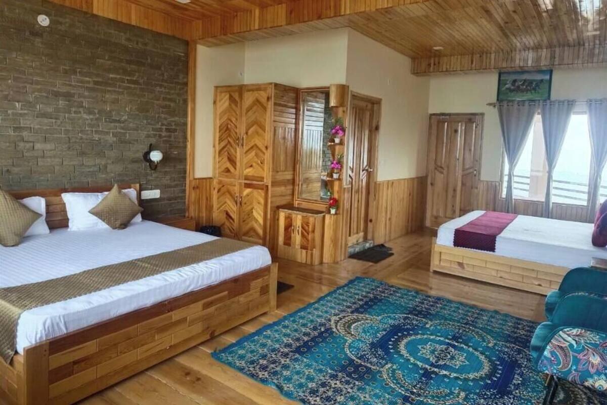 A wooden-themed bedroom with a large bed, a smaller bed, and a seating area.