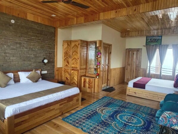 A wooden-themed bedroom with a large bed, a smaller bed, and a seating area.